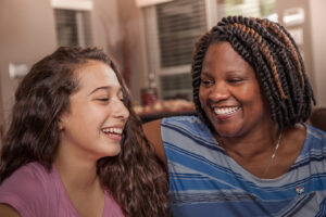 image of multi-ethnic family. Teenage girls and mom at home. Hugs.
